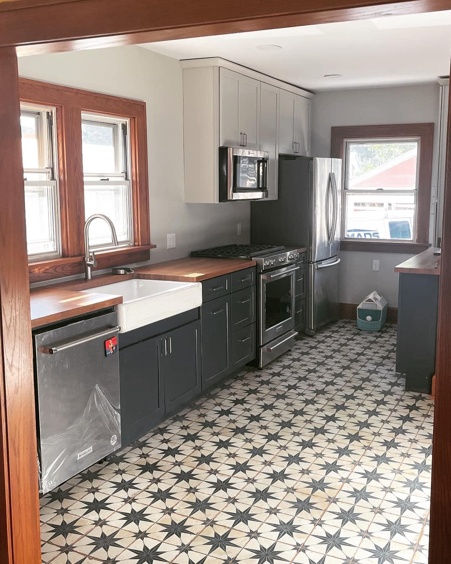 A kitchen with navy cabinets, a walnut counter and a patterned tile floor