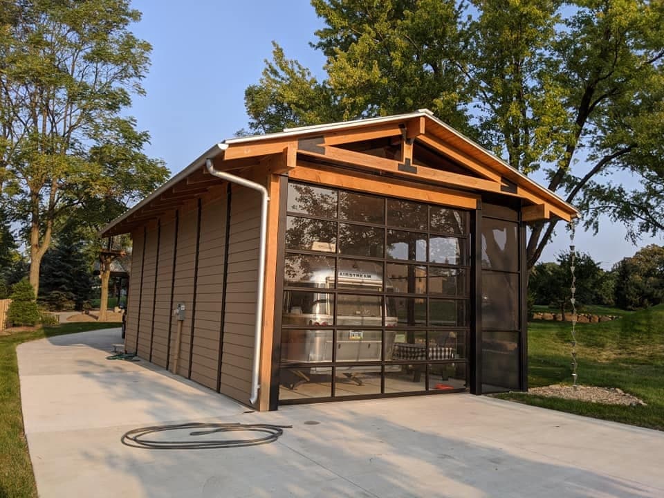 A detached garage with a glazed overhead door and an exposed timber truss