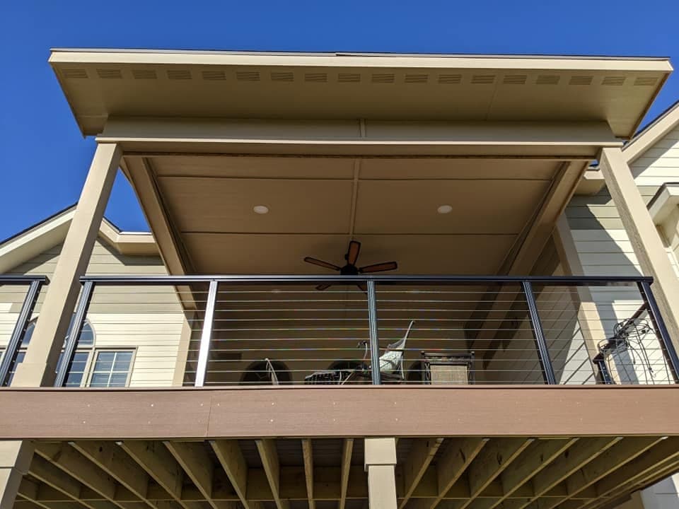 A covered deck with a cable railing and a ceiling fan